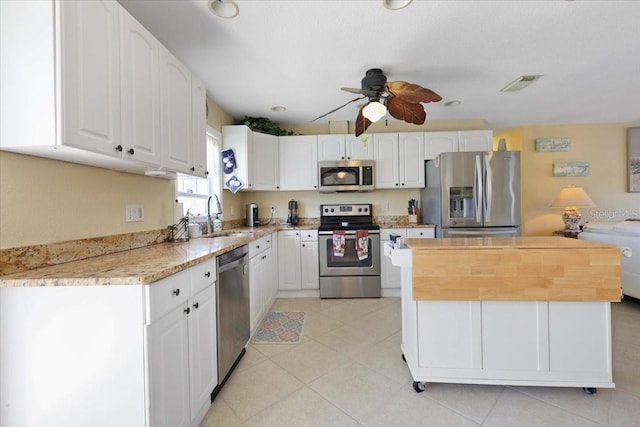 kitchen with sink, ceiling fan, appliances with stainless steel finishes, white cabinets, and a kitchen island