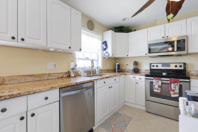 kitchen with light tile patterned floors, stainless steel appliances, sink, and white cabinets