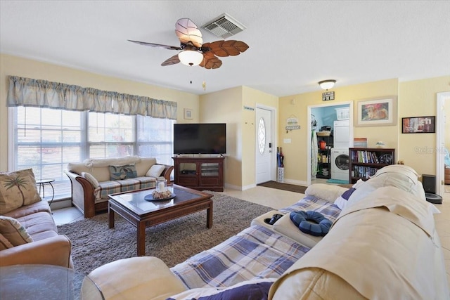 living room with stacked washer and clothes dryer and ceiling fan