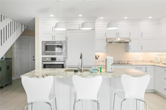 kitchen with stainless steel appliances, white cabinetry, and decorative light fixtures