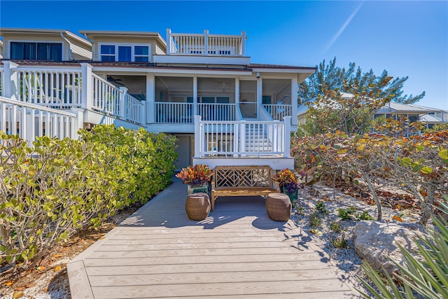 rear view of property featuring a wooden deck and a sunroom