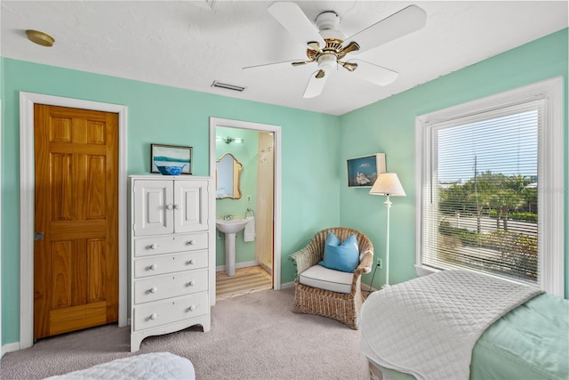 carpeted bedroom featuring ceiling fan, ensuite bath, and sink