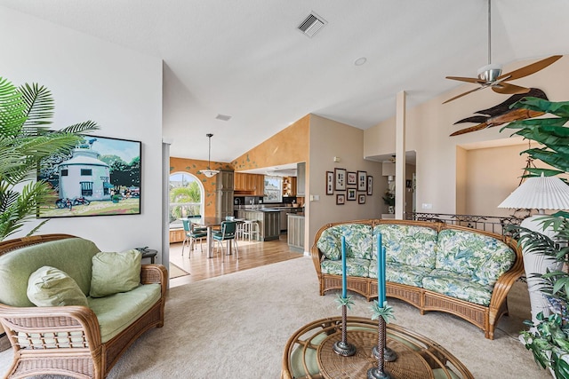 carpeted living room with ceiling fan and high vaulted ceiling