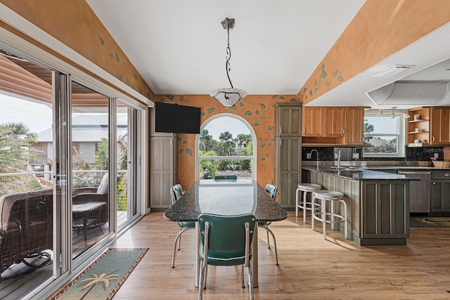 dining space with lofted ceiling, sink, and light hardwood / wood-style floors