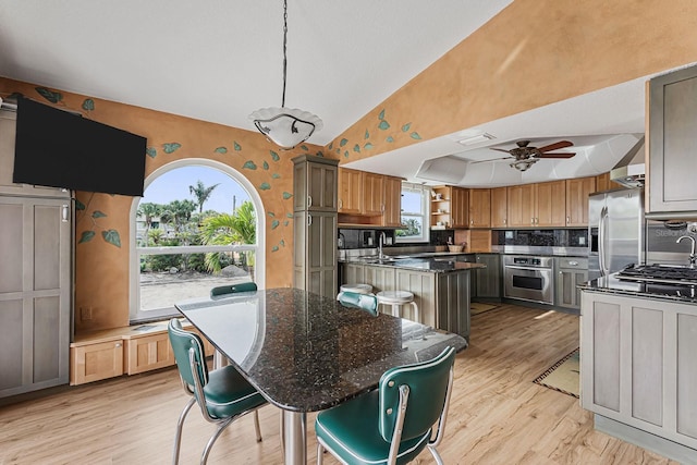 kitchen featuring appliances with stainless steel finishes, a breakfast bar, tasteful backsplash, hanging light fixtures, and a center island