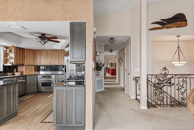 kitchen featuring pendant lighting, ceiling fan, appliances with stainless steel finishes, tasteful backsplash, and light colored carpet