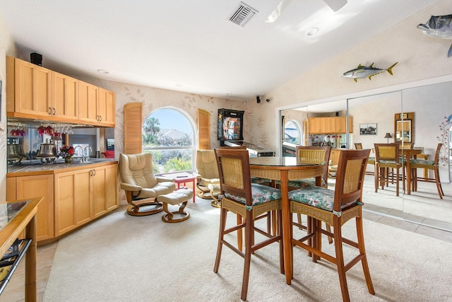 carpeted dining room with lofted ceiling and sink