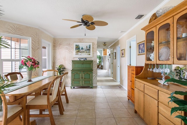 tiled dining space with crown molding, a textured ceiling, and ceiling fan