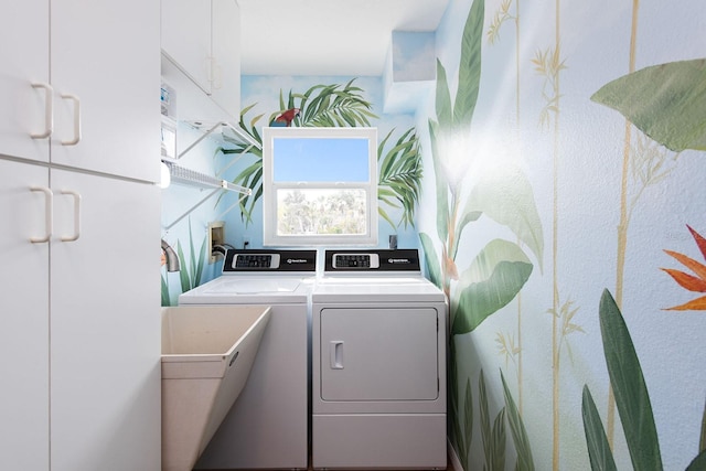 clothes washing area featuring cabinets and washing machine and clothes dryer