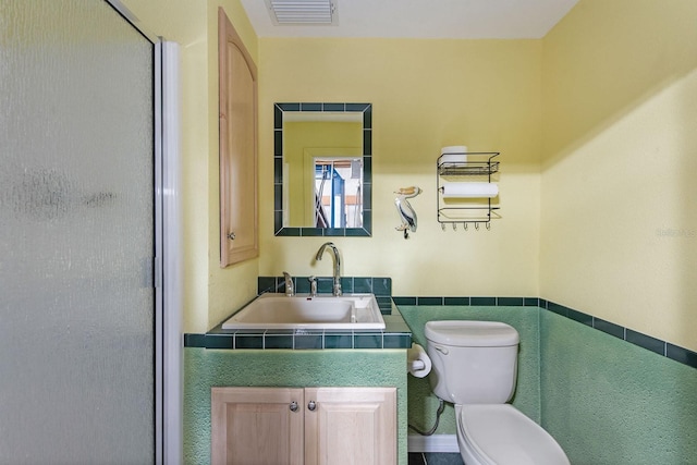 bathroom with walk in shower, sink, tile walls, and toilet