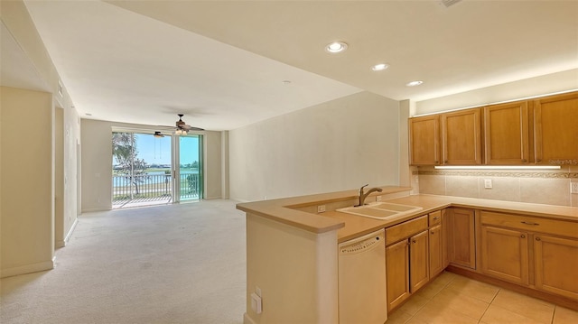 kitchen featuring sink, dishwasher, decorative backsplash, light colored carpet, and kitchen peninsula