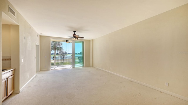 carpeted spare room featuring a water view and ceiling fan