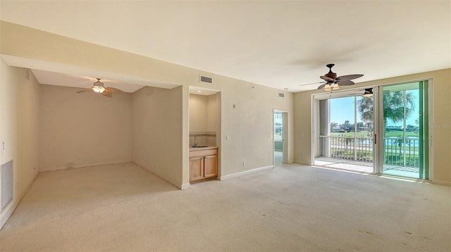 spare room with ceiling fan, sink, and light carpet