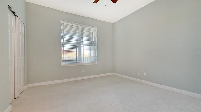 unfurnished bedroom with light carpet, lofted ceiling, a closet, and ceiling fan