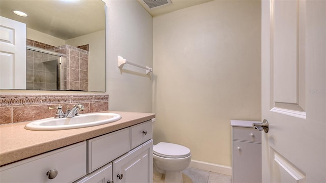 bathroom featuring tile patterned flooring, vanity, a shower with shower door, and toilet