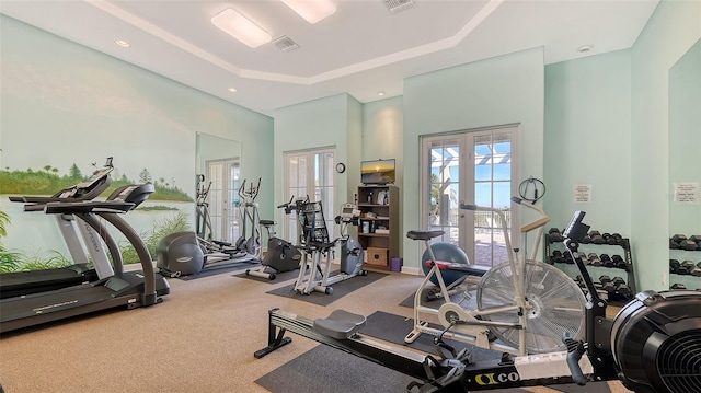 gym with a raised ceiling, carpet, and french doors