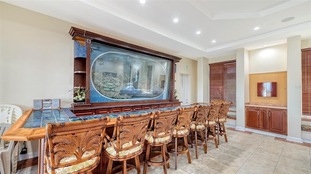 bar with light tile patterned flooring and a tray ceiling