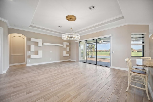 unfurnished living room featuring a tray ceiling, a wealth of natural light, and light wood-type flooring