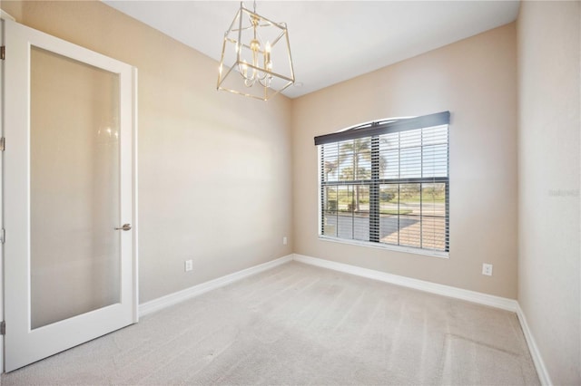 spare room with a notable chandelier and carpet floors