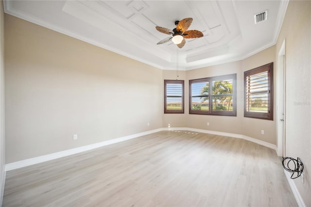 unfurnished room with a raised ceiling, ornamental molding, ceiling fan, and light wood-type flooring