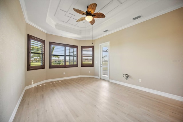 empty room featuring crown molding, ceiling fan, a raised ceiling, and light wood-type flooring