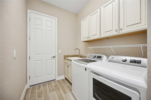 clothes washing area with washer and dryer, sink, and cabinets