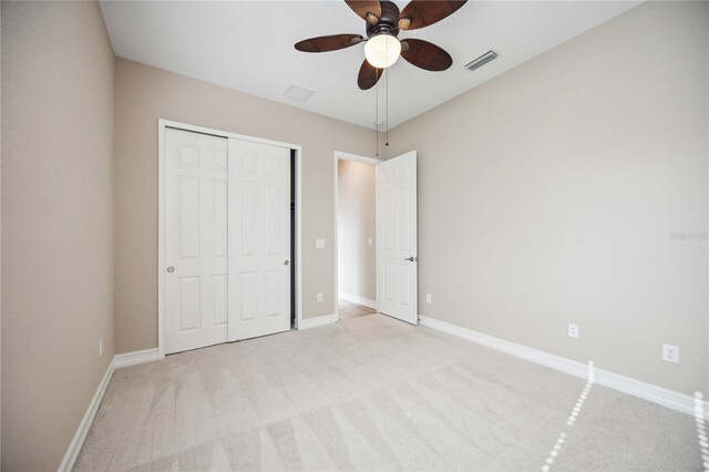 unfurnished bedroom featuring light colored carpet, a closet, and ceiling fan