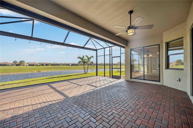 view of patio featuring a water view, ceiling fan, and glass enclosure