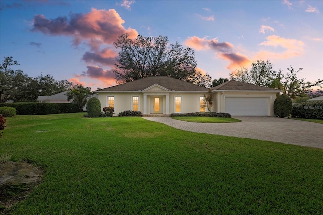 ranch-style home with a garage and a lawn