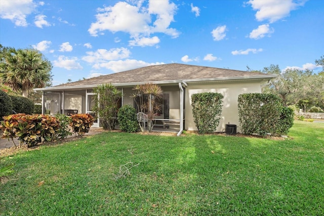 back of house featuring a sunroom and a lawn