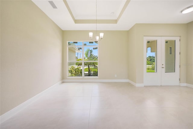 interior space featuring french doors, a tray ceiling, light tile patterned flooring, and an inviting chandelier