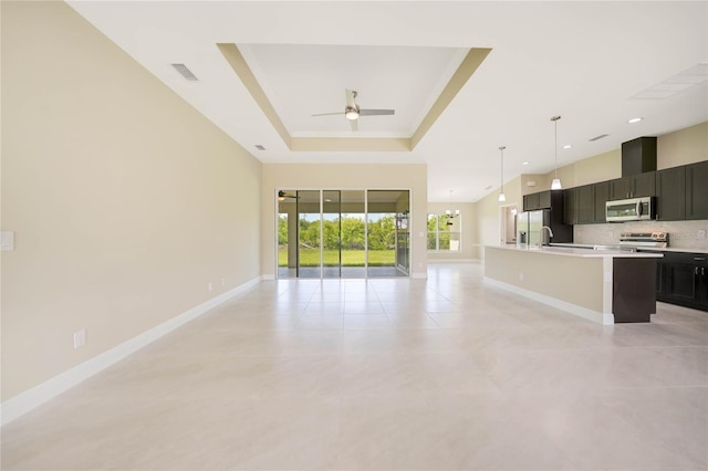 unfurnished living room featuring a raised ceiling, sink, light tile patterned floors, and ceiling fan