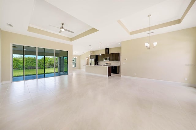 unfurnished living room featuring light tile patterned floors, ceiling fan with notable chandelier, and a raised ceiling