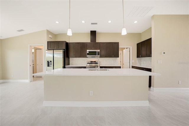 kitchen featuring dark brown cabinetry, tasteful backsplash, hanging light fixtures, a center island with sink, and stainless steel appliances