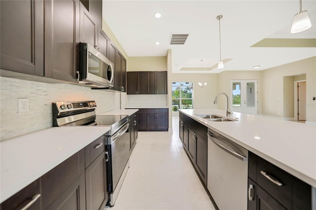 kitchen with sink, dark brown cabinets, a tray ceiling, pendant lighting, and stainless steel appliances