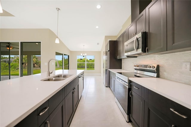 kitchen featuring sink, backsplash, stainless steel appliances, light tile patterned flooring, and decorative light fixtures