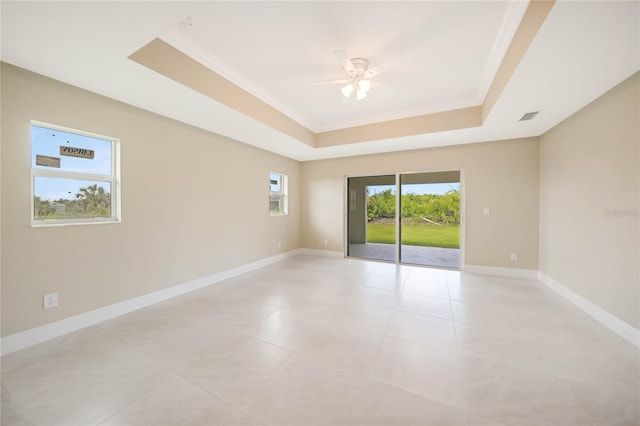 spare room featuring light tile patterned flooring, ceiling fan, ornamental molding, and a tray ceiling