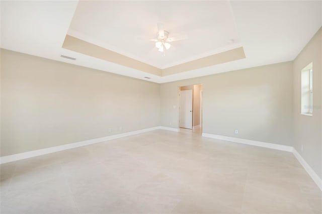 tiled spare room featuring a raised ceiling and ceiling fan