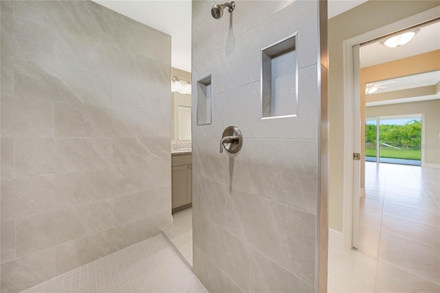 bathroom with a tile shower, vanity, and tile patterned flooring