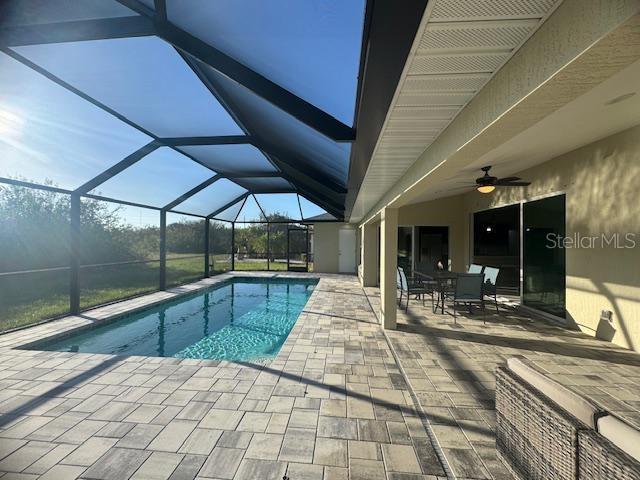 view of pool featuring a patio, ceiling fan, and glass enclosure