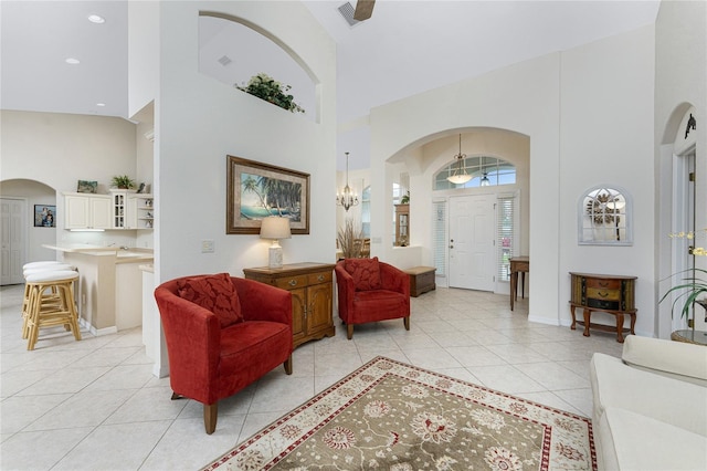 living room featuring light tile patterned floors, a notable chandelier, and a high ceiling