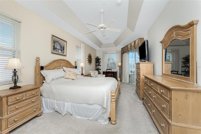 carpeted bedroom with ceiling fan and a tray ceiling