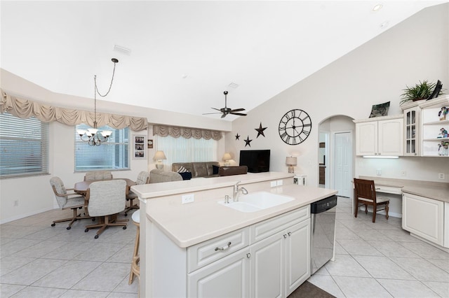 kitchen with lofted ceiling, sink, dishwasher, hanging light fixtures, and an island with sink