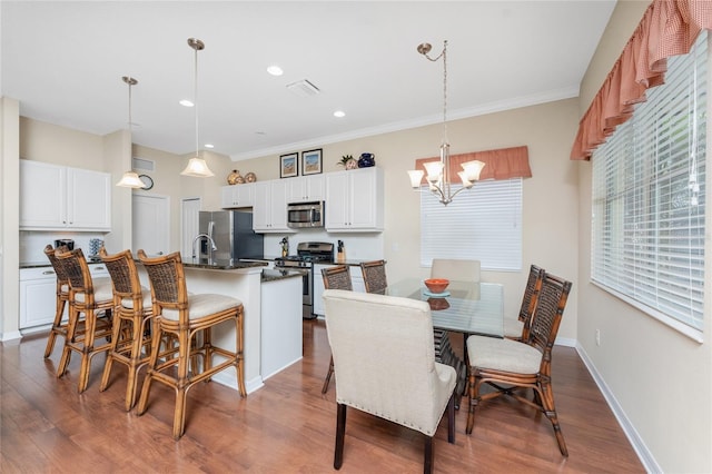 dining room featuring an inviting chandelier, ornamental molding, and wood-type flooring