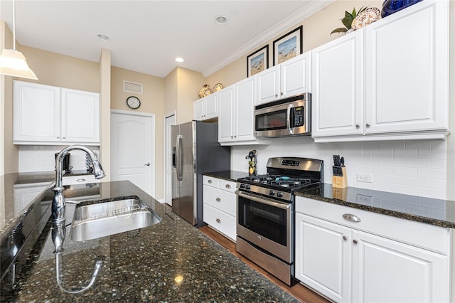 kitchen with pendant lighting, sink, appliances with stainless steel finishes, white cabinetry, and dark stone counters