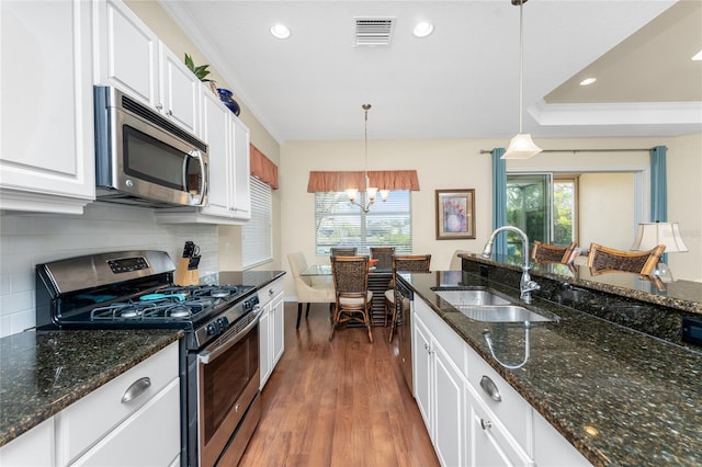 kitchen featuring pendant lighting, sink, appliances with stainless steel finishes, white cabinets, and dark stone counters