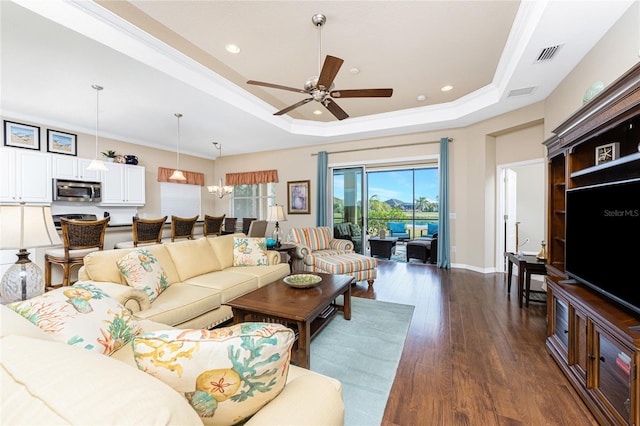 living room with a tray ceiling, dark wood-type flooring, ornamental molding, and ceiling fan