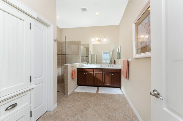 bathroom with tile patterned flooring, vanity, and tiled shower