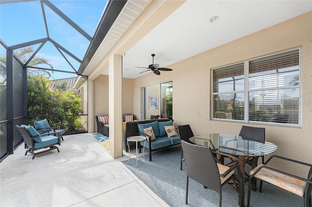 view of patio featuring ceiling fan, an outdoor living space, and glass enclosure