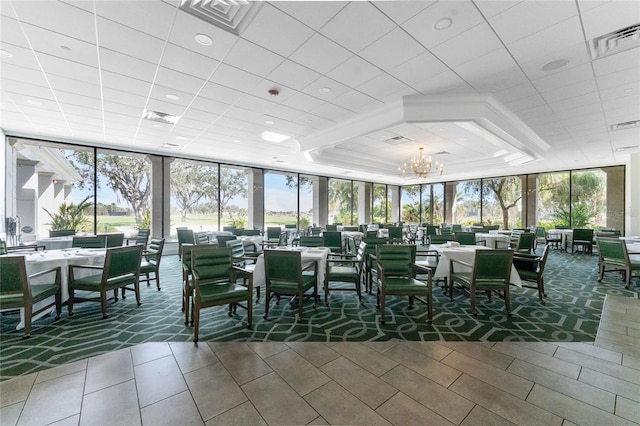 unfurnished sunroom featuring a raised ceiling, plenty of natural light, and a notable chandelier